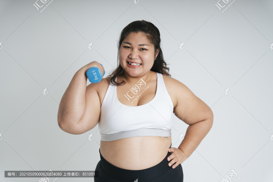 亚洲胖女人在白色运动胸罩运动与蓝色哑铃白色背景。