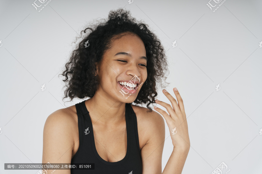在白色背景上，身着黑色运动胸罩的快乐欢笑的非洲妇女的肖像。