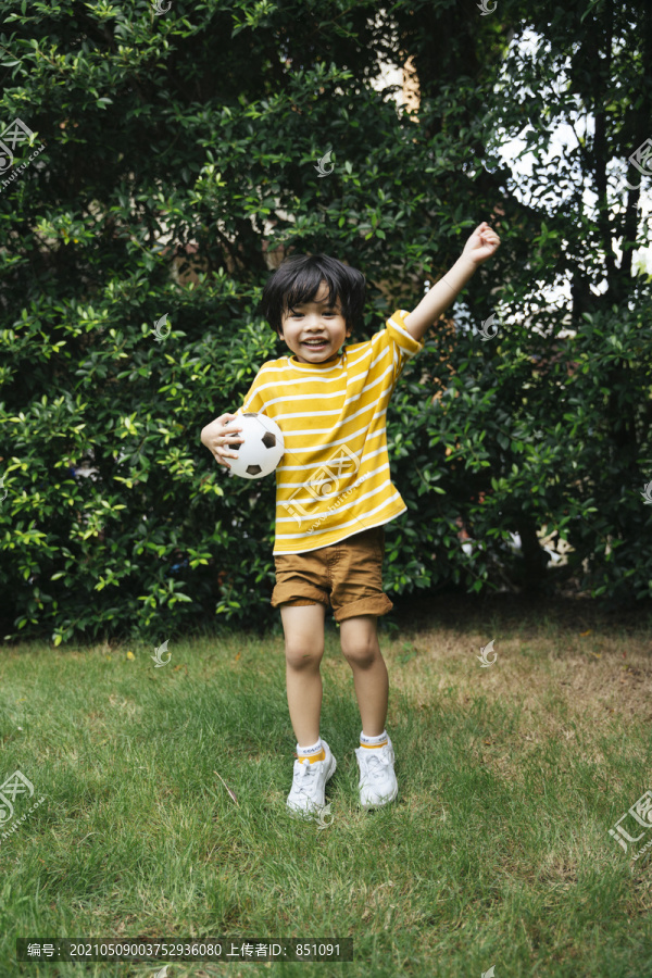 一个快乐的亚洲小孩拿着一个球，脸上带着兴奋的表情。