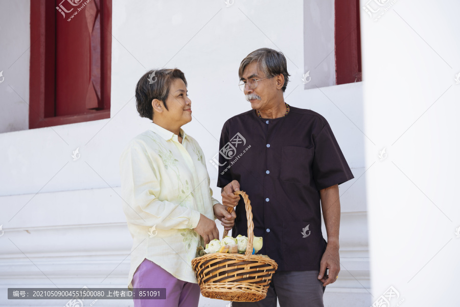浪漫的亚洲老年夫妇手持莲花篮在寺庙里献礼。