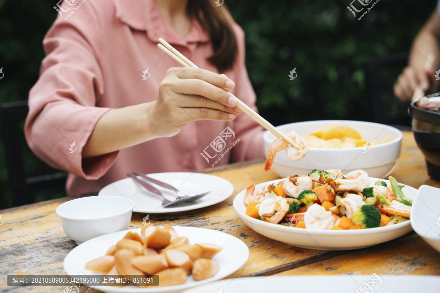女人用筷子吃炒菜和香肠。