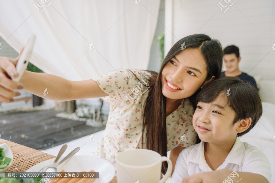 亚泰母子一边吃午饭一边用智能手机自拍。