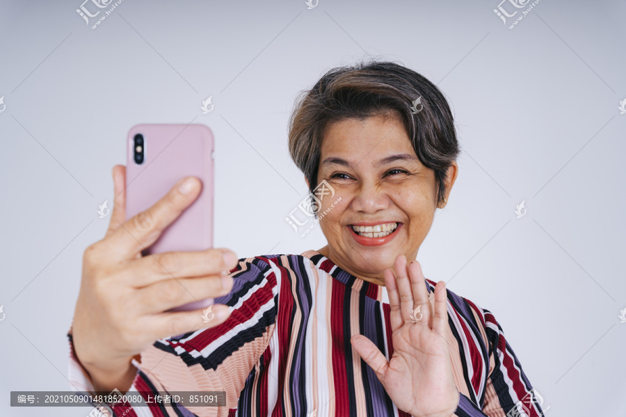 快乐的老年妇女自拍或用智能手机聊天。