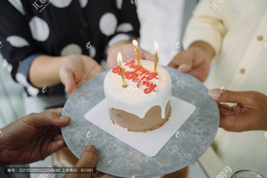 生日快乐蛋糕与蜡烛与人们的手包围。