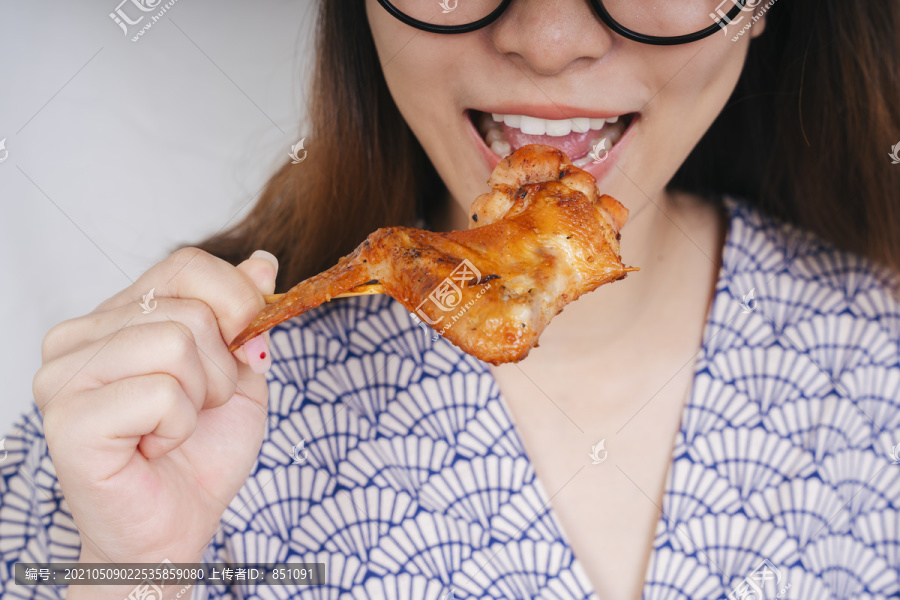 特写镜头：一位年轻的亚洲妇女正在美味地吃着烤鸡。