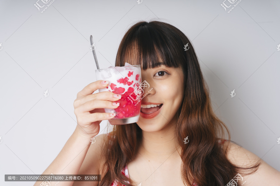 亚洲年轻女子手持一杯荸荠甜点的画像。