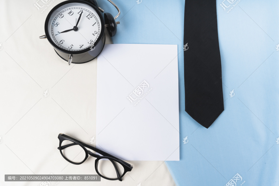 顶视图-带时钟和眼镜的实物模型用纸，并系在蓝色背景上。商人概念。