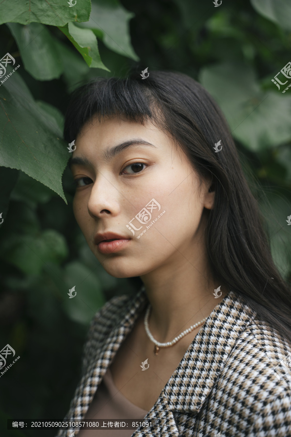 身着绿叶背景正式衬衫的女商人的特写肖像。