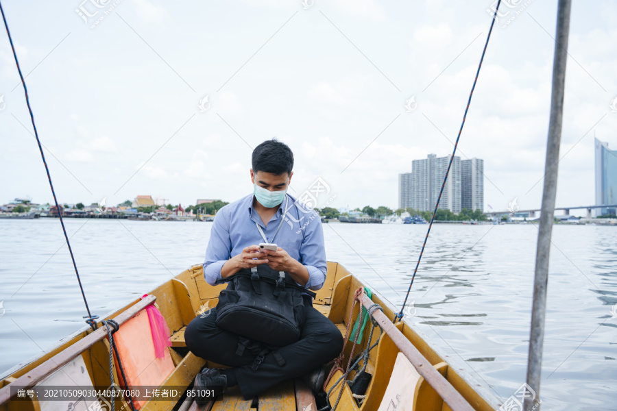 亚洲商人戴着面具在曼谷乘船旅行。