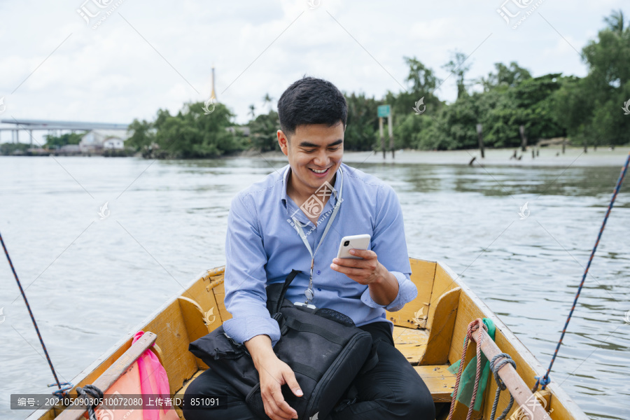 在泰国曼谷，一位亚洲商人正在使用电话和乘船旅行。