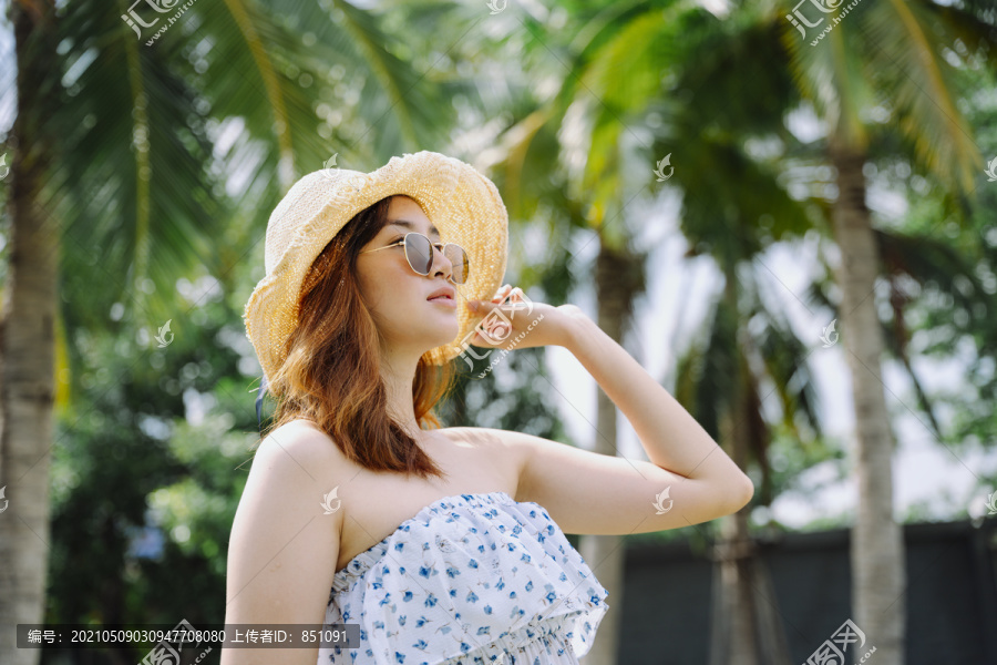 美丽的亚洲女游客的肖像，戴着墨镜和帽子在户外度假胜地。