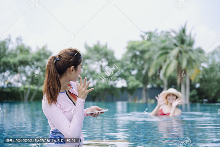 美丽的亚洲女游客喜欢和朋友在室外游泳池游泳。