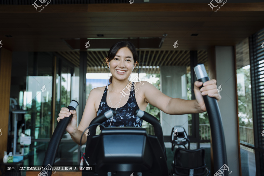 快乐美丽健康的女人在室内健身自行车上锻炼。