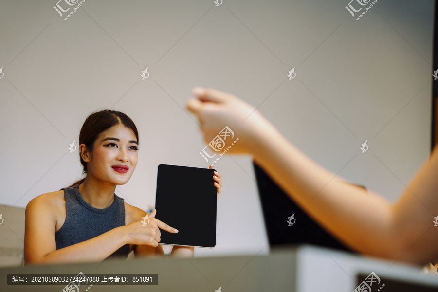 亚洲女商务人士在会议上向客户展示笔记本电脑屏幕。