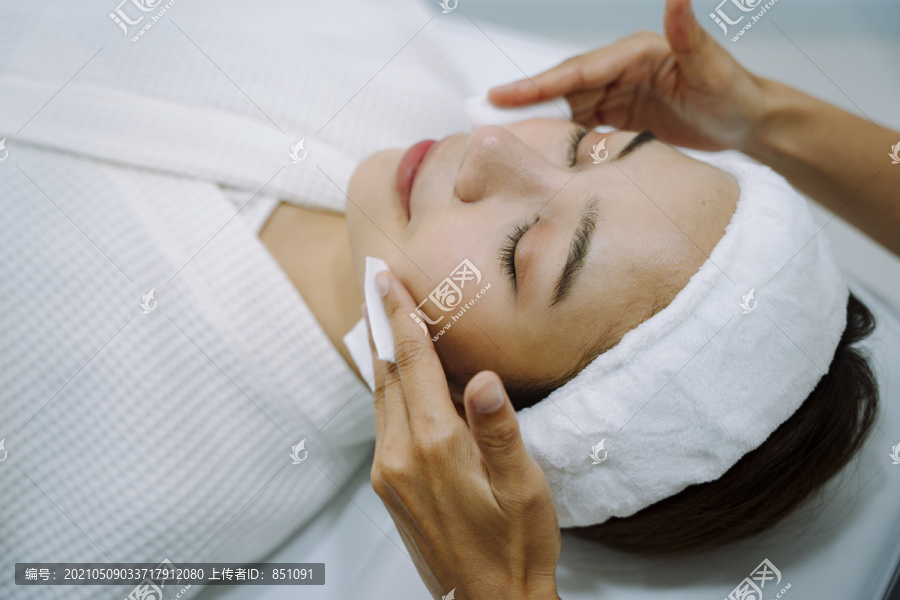 美容师在美容诊所和水疗中心用化妆棉洗脸。