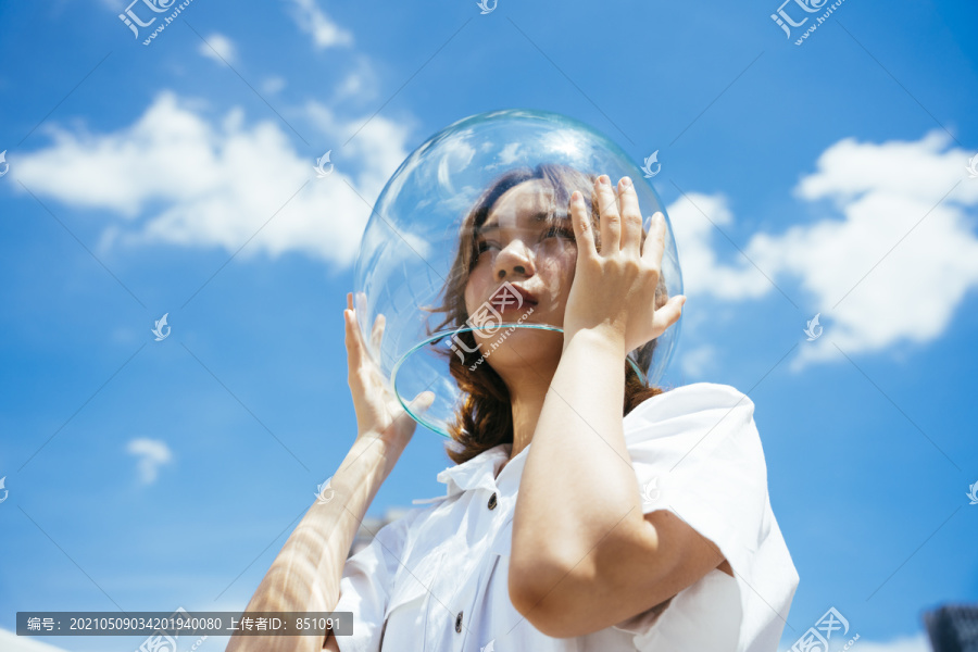 一位戴着玻璃碗的亚裔妇女像宇航员一样保护自己免受地球上的污染。