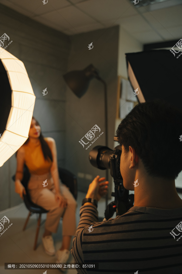 年轻的亚洲摄影师和模特在暗室摄影棚拍摄。