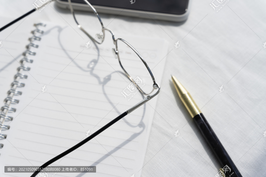 顶视图-带眼镜和金笔的商务人员办公桌。