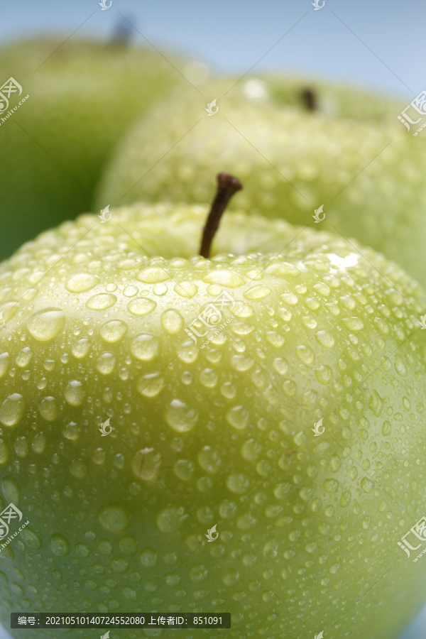 在彩色背景上被水滴覆盖的湿绿色苹果。隔离。