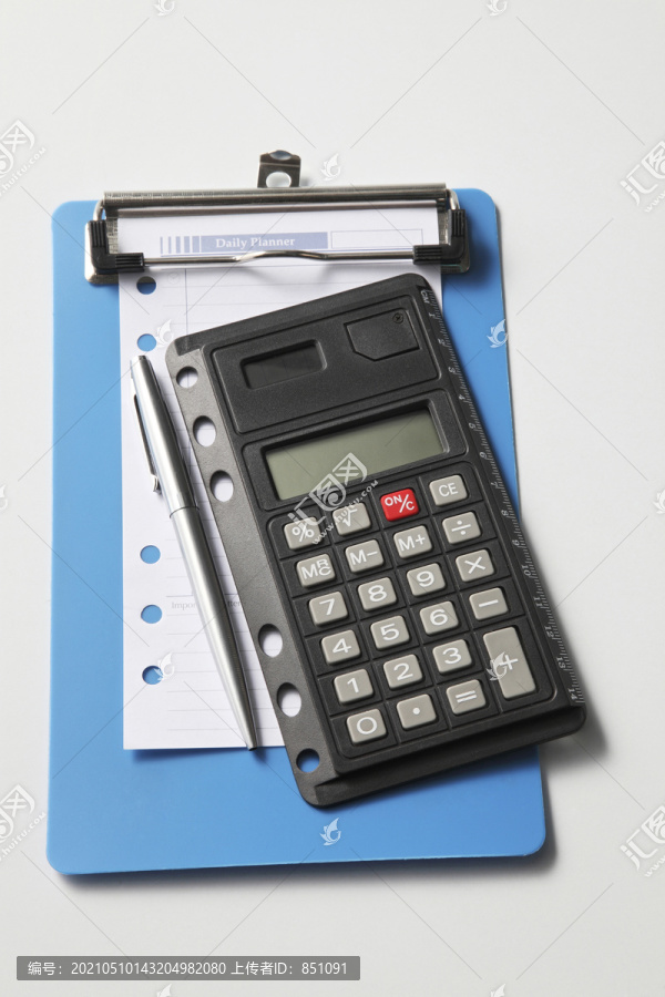 空白的每日计划笔记，用钢笔和计算器放在夹板上。