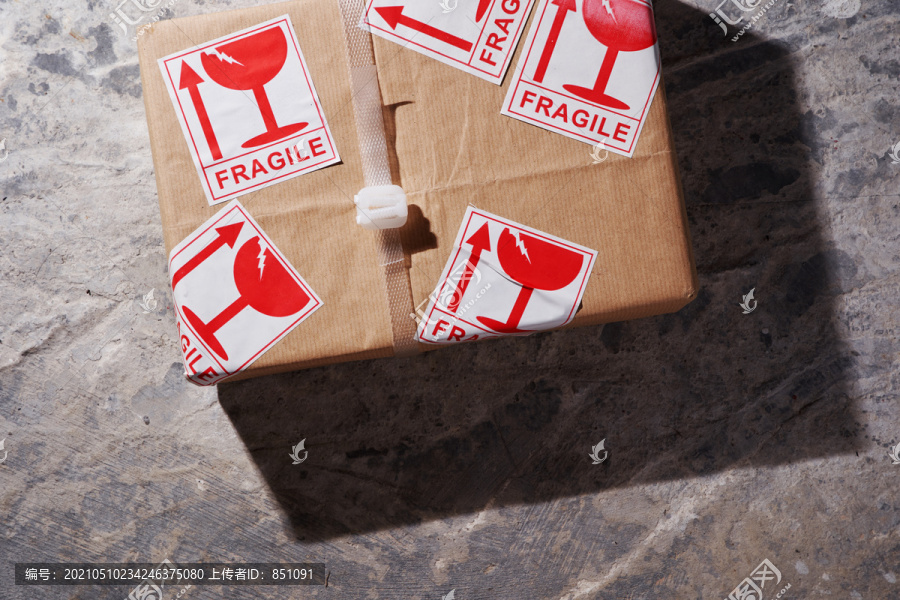 水泥地面上贴着易碎标签的棕色盒子包裹