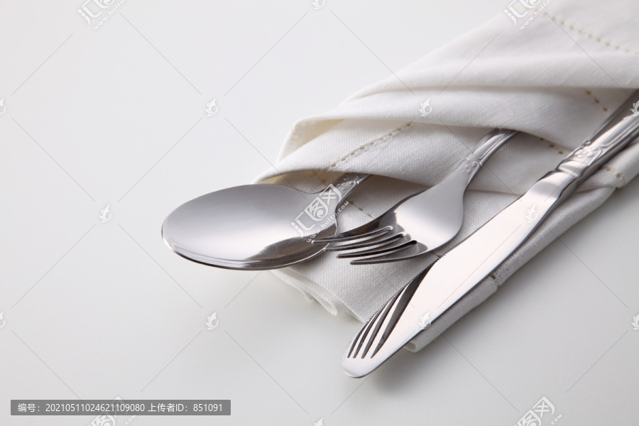 白色背景的折叠餐巾，带叉子、勺子和刀