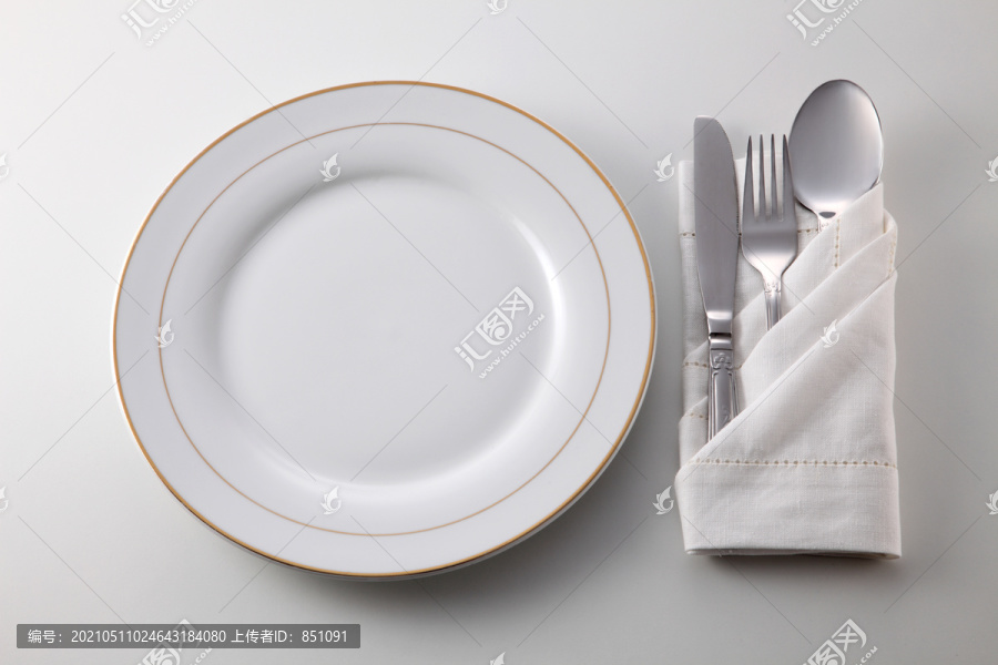 折叠餐巾，餐叉、汤匙和刀子放在盘子旁边