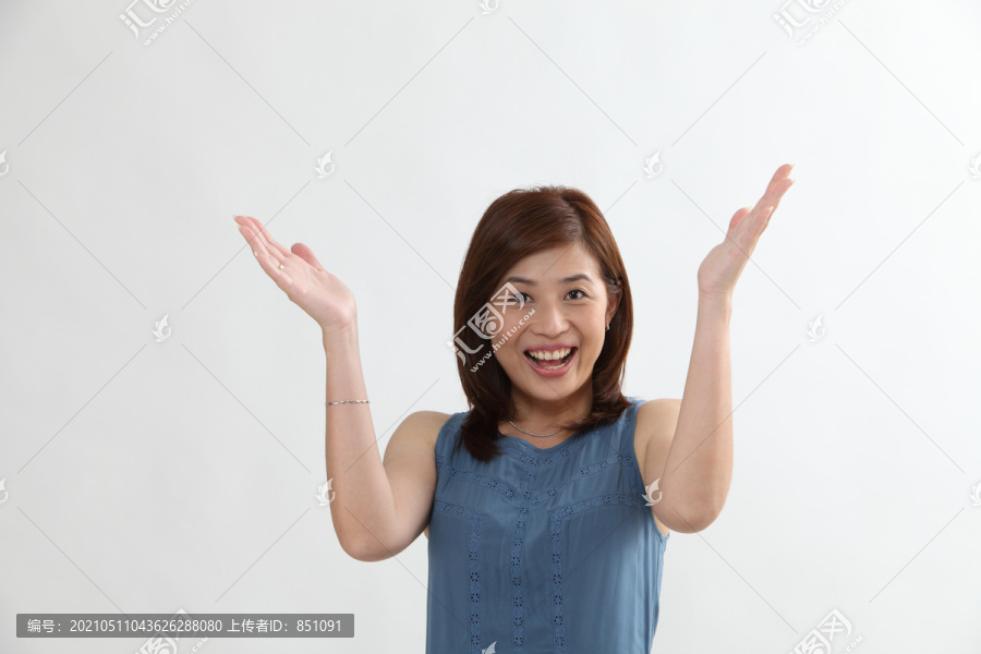 一位中国妇女举着胳膊微笑着看着摄像机