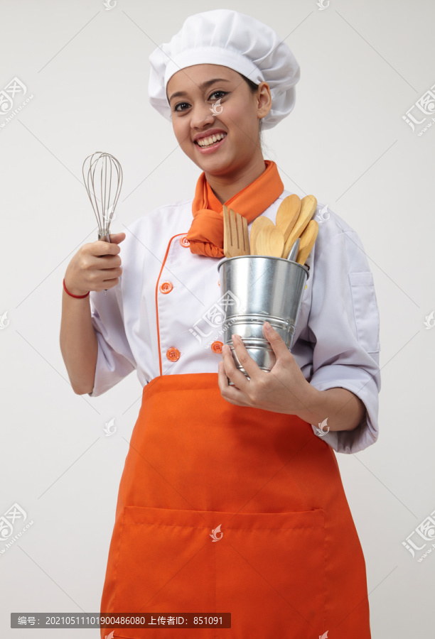 一个穿着厨师制服拿着搅拌器和抹刀的印度女人的肖像