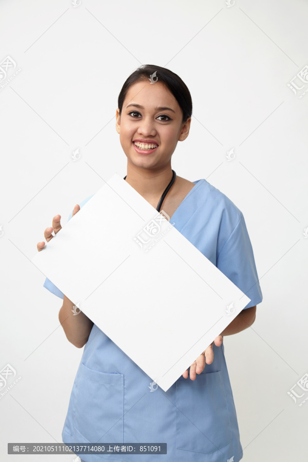 护士站着展示医疗标志的广告牌，年轻微笑的女护士或医生在擦洗台上展示空白的带有复印空间的广告牌。白色背