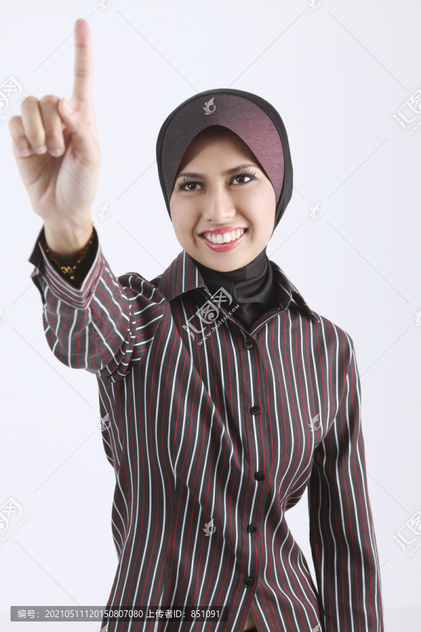 一个年轻的女人戴着图东和一个马来西亚手势