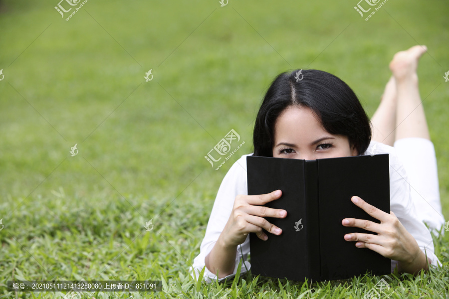 年轻女子用书遮住脸