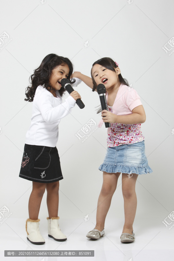 两个女孩对着麦克风唱歌