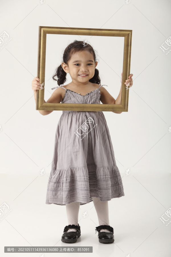 拿着金相框的女孩，透过镜子看