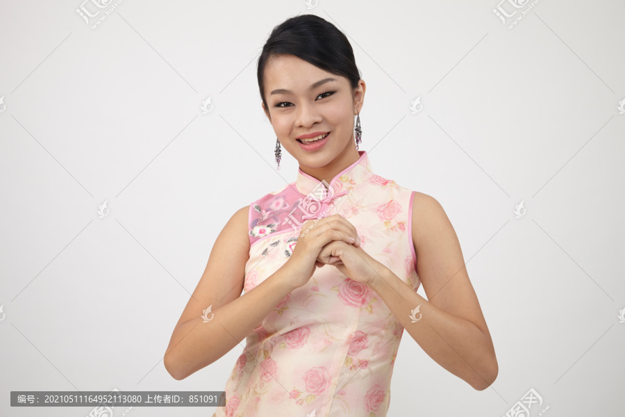 微笑的中国妇女在新年穿传统旗袍，摄影棚拍摄的白色背景上孤立。