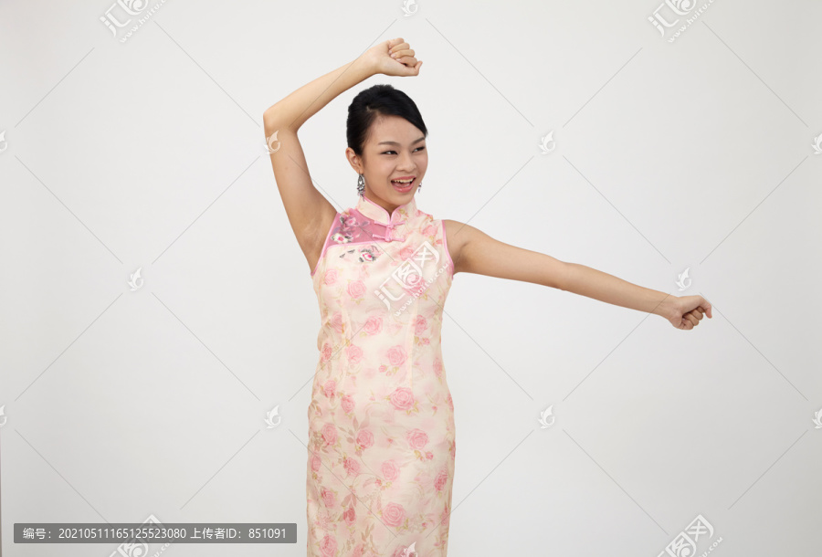 微笑的中国妇女在新年穿传统旗袍，摄影棚拍摄的白色背景上孤立。