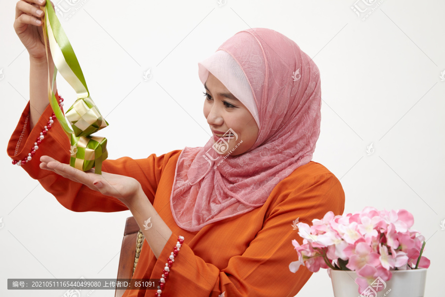 亚洲穆斯林马来妇女，白色背景上有图东图案，手持装饰性的斗篷