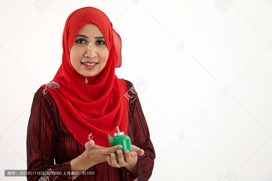 一名马来妇女手持佩利塔，身穿红色八珠裤