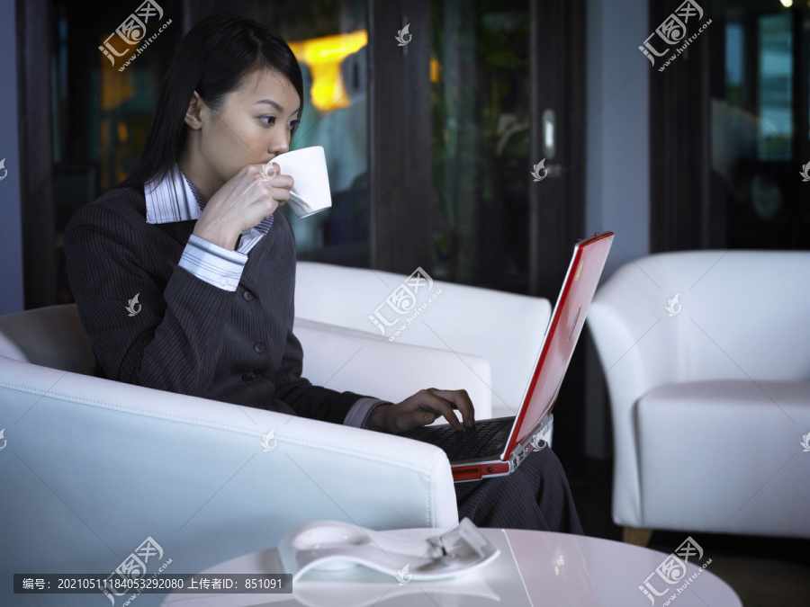 女商人一边用笔记本电脑一边喝咖啡