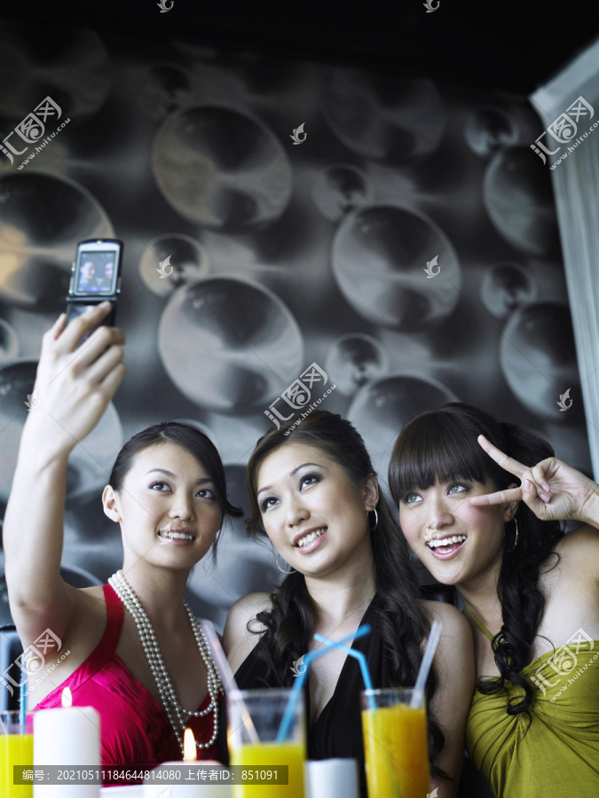三个年轻女子用照相手机拍照