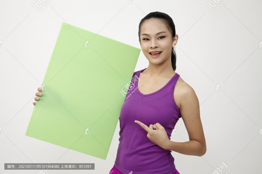 一位穿着运动服的中国年轻女子，白色背景上有一块空白的白板。是时候健身了。