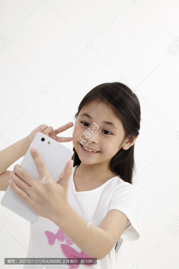 童年与科技。使用智能手机的可爱小女孩。隔离在白色上。