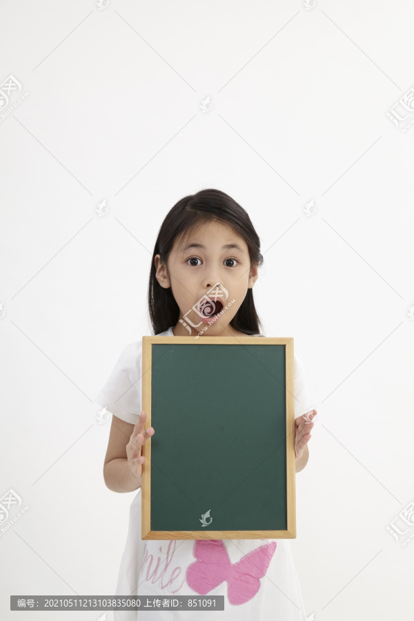 可爱的小女孩拿着黑板，孤零零地站在白色的地板上