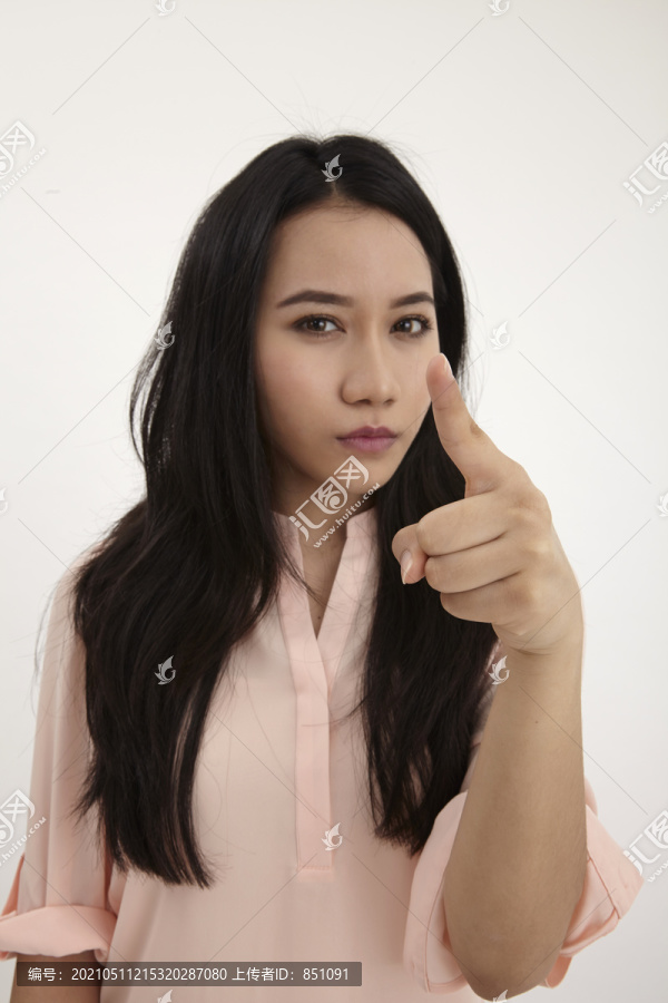 一个愤怒的年轻女子指着隔离在白色背景上的摄像机的肖像