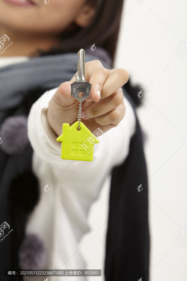 拿着房子形状钥匙圈的女人的特写镜头