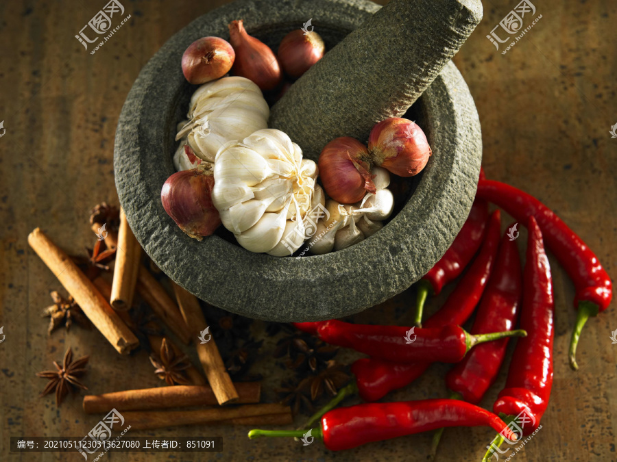 大蒜素和洋葱放在磨石机里，旁边放着红辣椒和香料