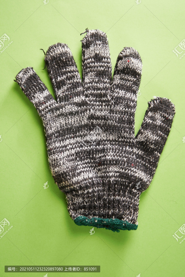 一块隔离在绿色背景上的织物工作手套。