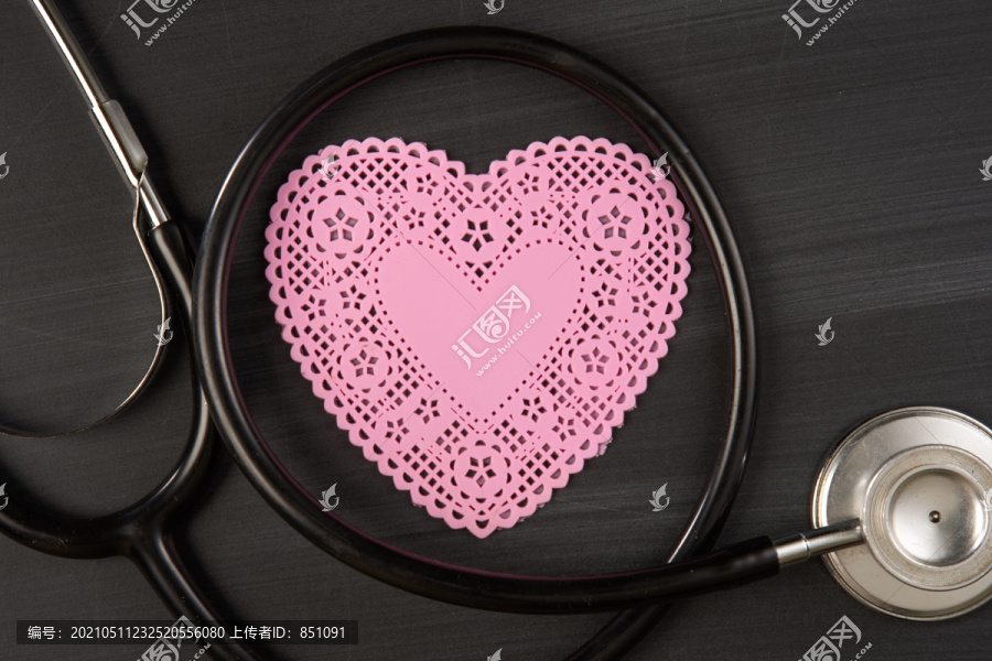 听诊器特写，粉色心形心形艺术剪纸在黑板上