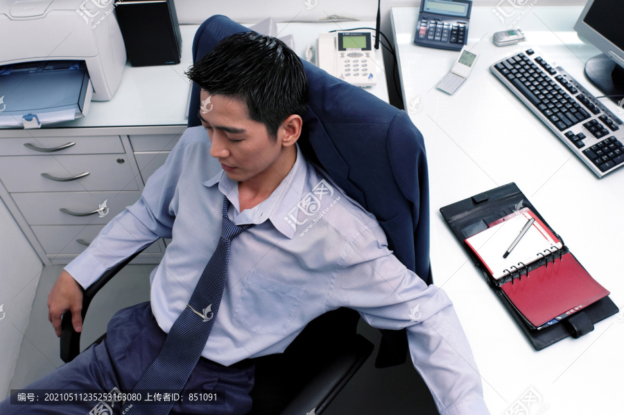 一个穿着蓝色衬衫的男人坐在桌子旁睡觉