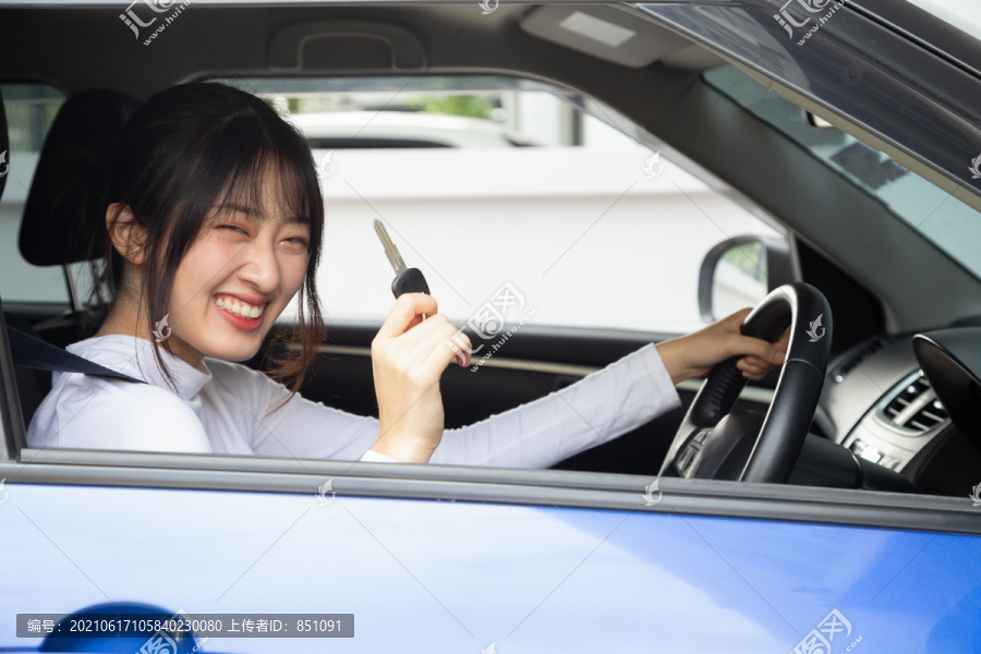 年轻快乐的亚洲汽车女司机微笑着出示新车钥匙。新手驾驶人概念